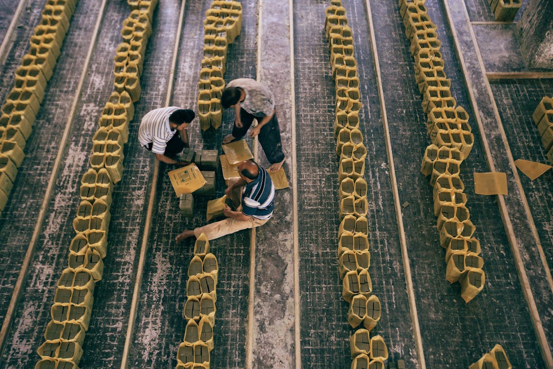 Manufacturing facility workers collaborating on production floor with industrial equipment