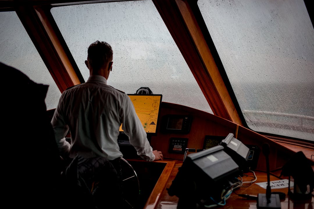 Experienced ship captain at wheel navigating through stormy seas representing leadership through challenges