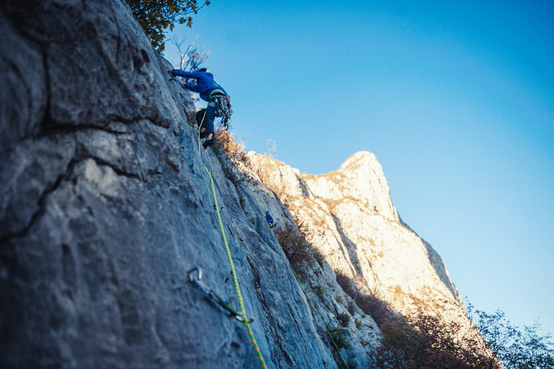 Person climbing steep mountain face representing navigation of corporate approval hierarchy