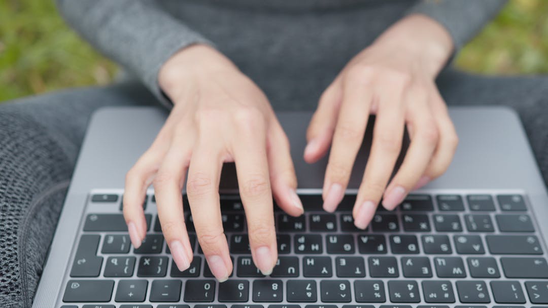 Close-up of focused hands typing on laptop keyboard implementing business strategy