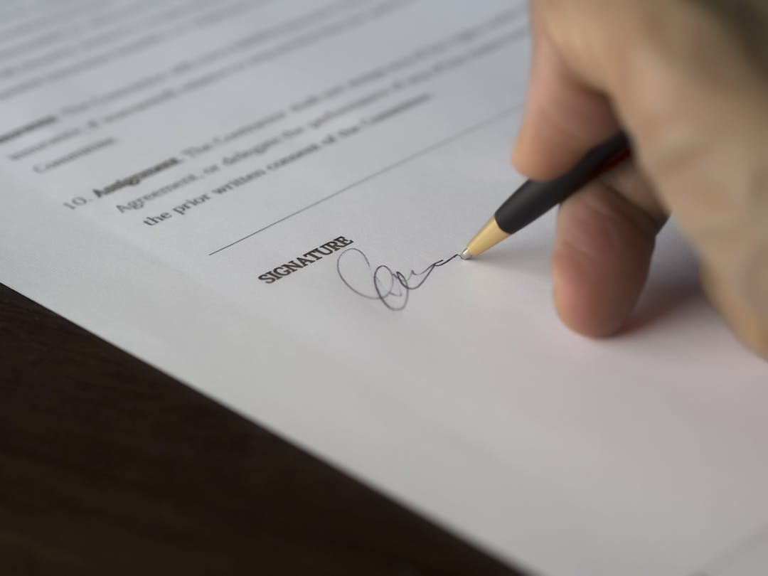 Close-up of pen signing contract document on desk