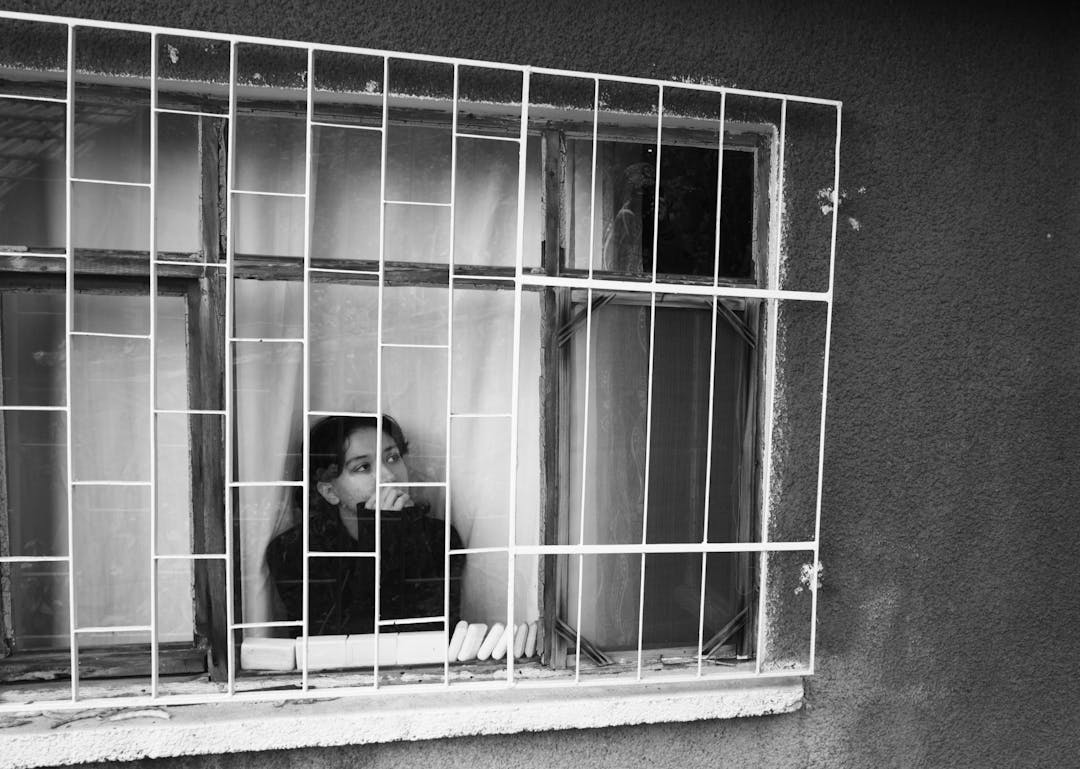 Thoughtful individual gazing out window, reflecting on major life transition