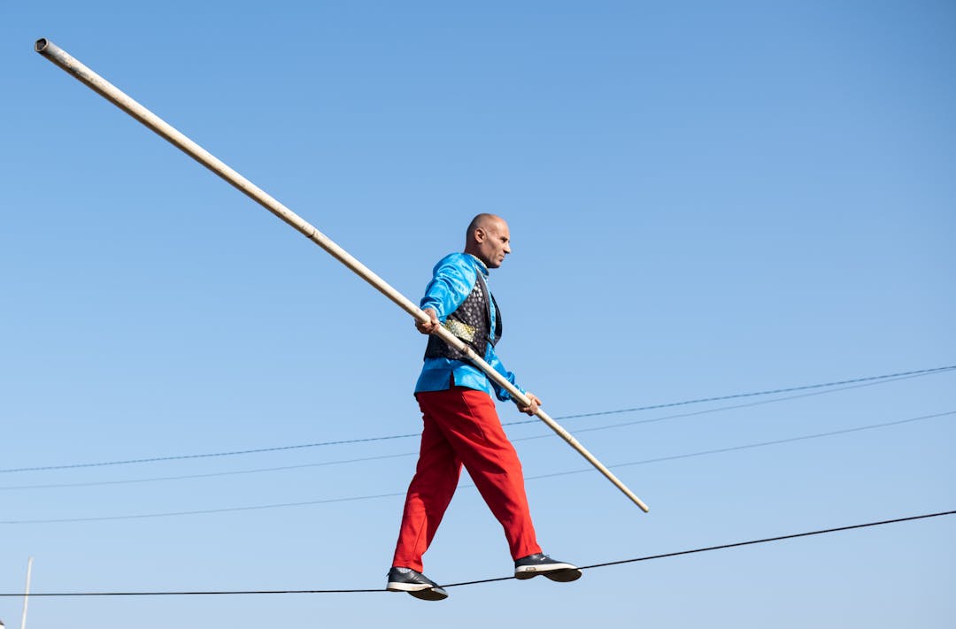 Silhouetted figure walking tightrope against sky representing balance between disclosure and negotiation