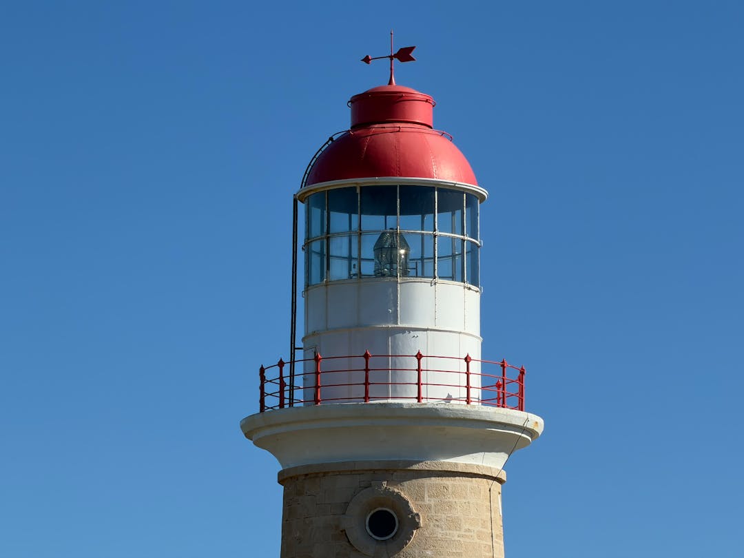 Lighthouse beam cutting through darkness to guide ships away from rocky coastline