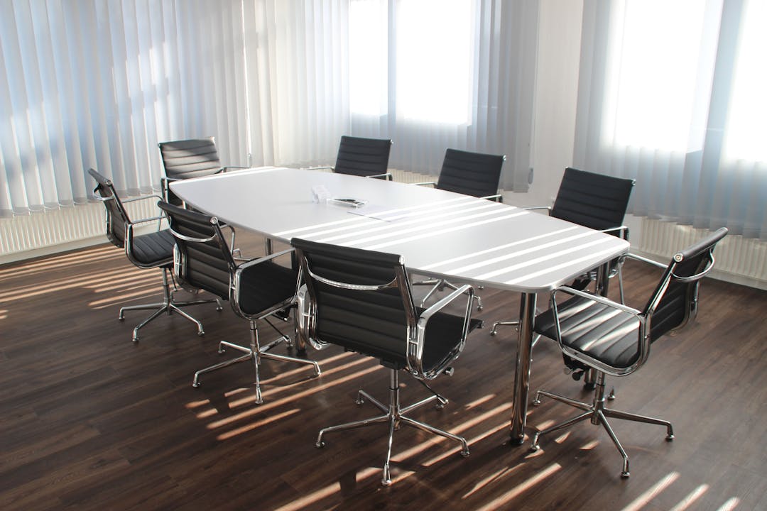 Empty conference table with scattered papers, suggesting missed communication