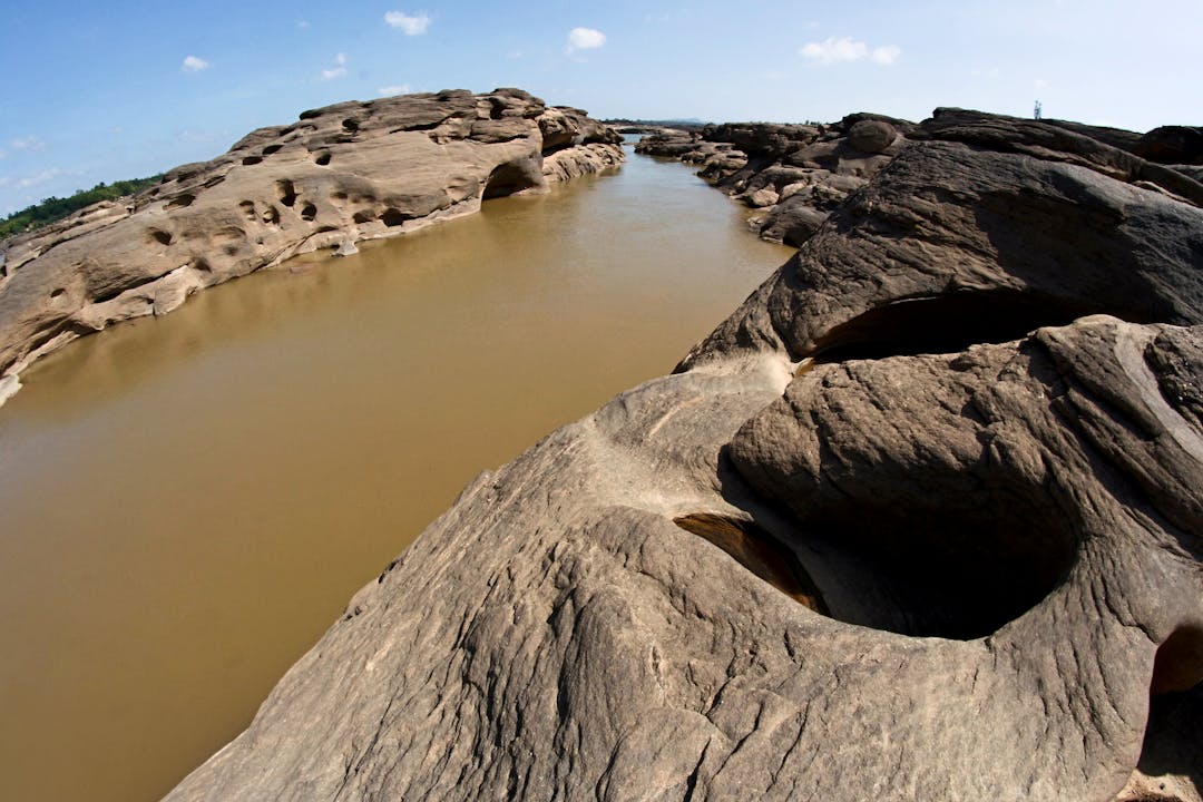 Water gradually eroding rock face showing slow but persistent change over time