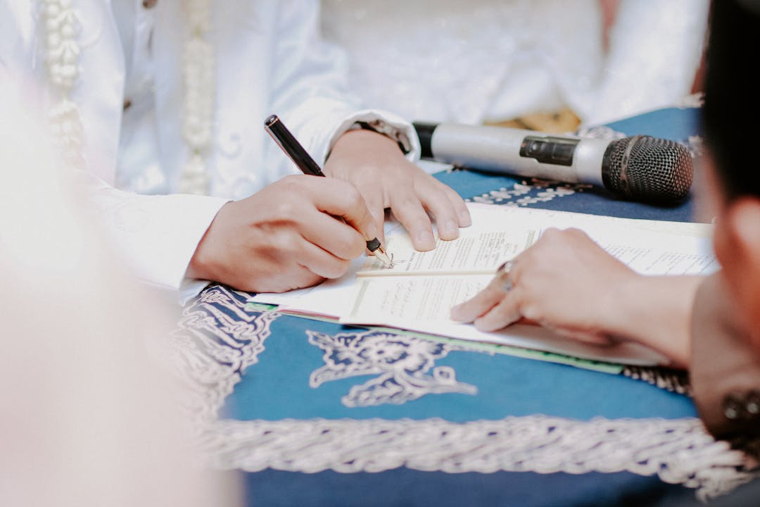 Professional hands signing legal documents with pen on wooden desk