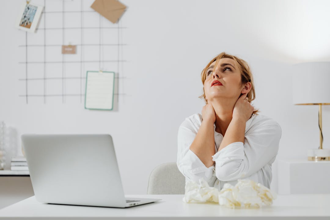 Business professional looking stressed while taking multiple urgent phone calls at desk