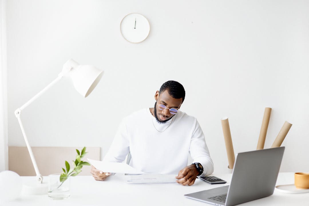 Business owner reviewing financial documents with confused expression at desk