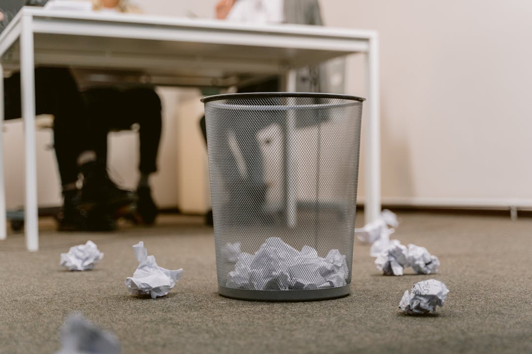 Disorganized stack of business documents and papers scattered across wooden desk surface