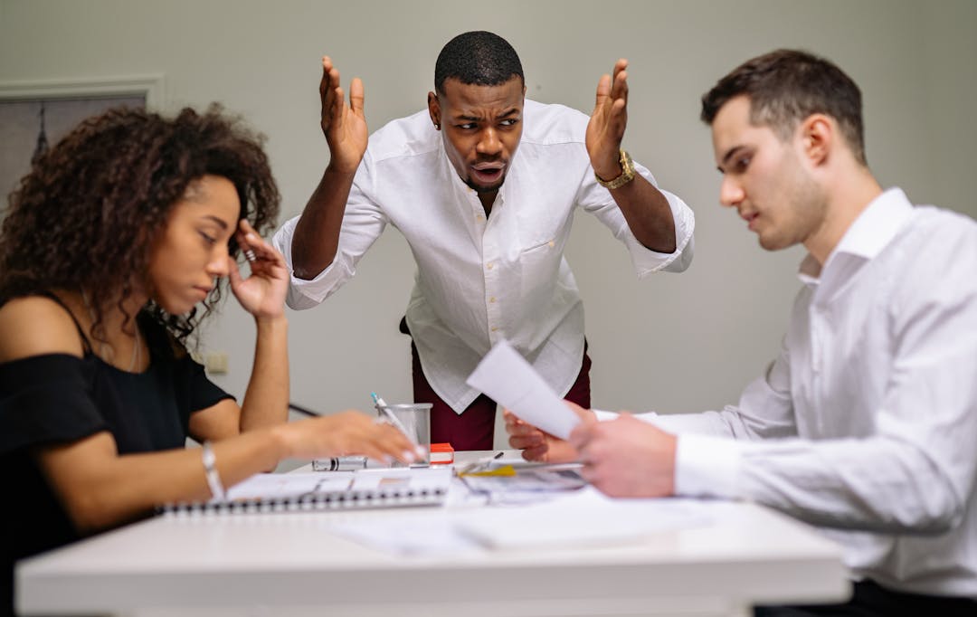 Two professionals in serious discussion across a table, showing tension and uncertainty during negotiation