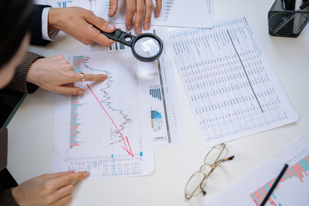 Business owner carefully examining financial statements and transaction documents at desk