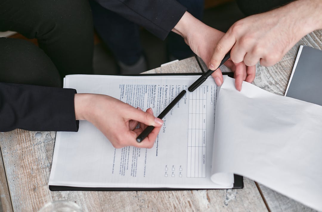 Close-up of hands reviewing and signing contract documents at table