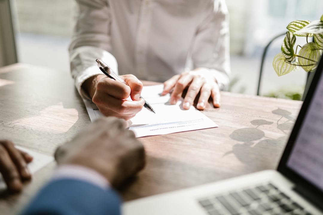 Two professionals in business discussion across table reviewing documents