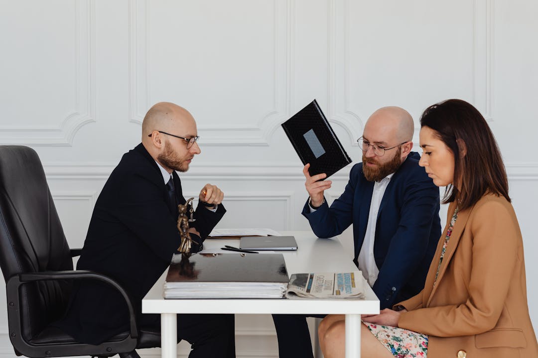 Two business people in disagreement across table with documents and papers scattered