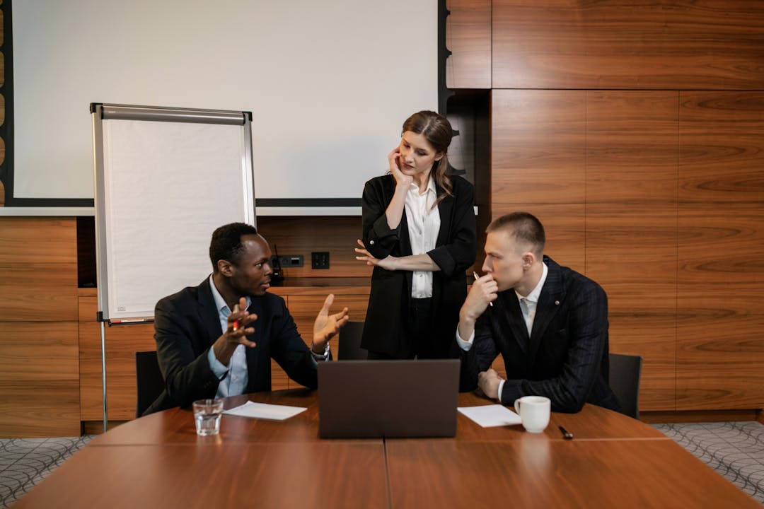 Two professionals in focused discussion at table during negotiation meeting