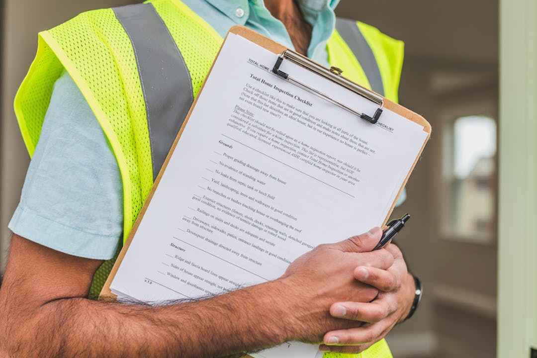 Professional person marking items on checklist with pen and clipboard
