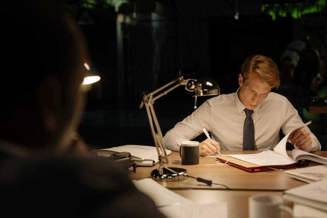 Business owner studying financial records and documentation at desk, contemplative expression