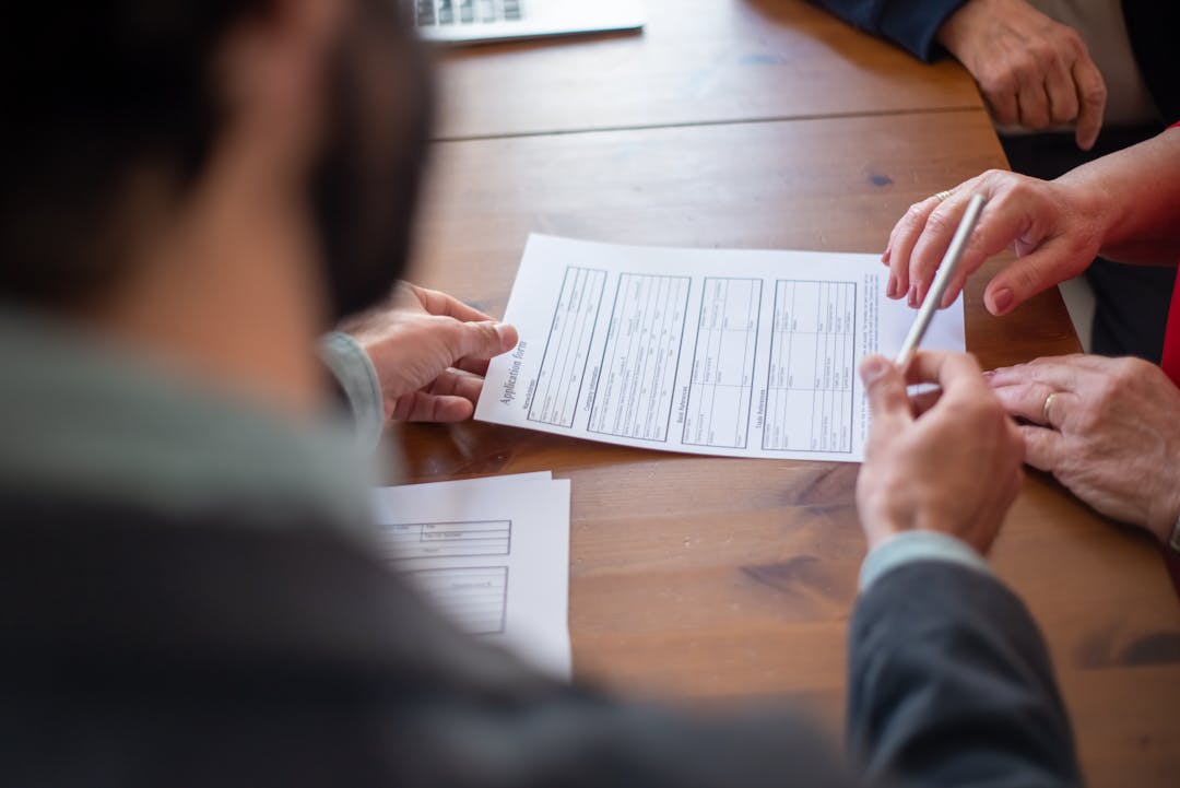 Team members discussing document details around conference table together