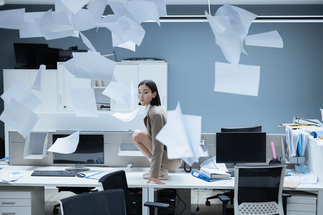 Disorganized stack of forgotten documents and files scattered across a cluttered desk surface
