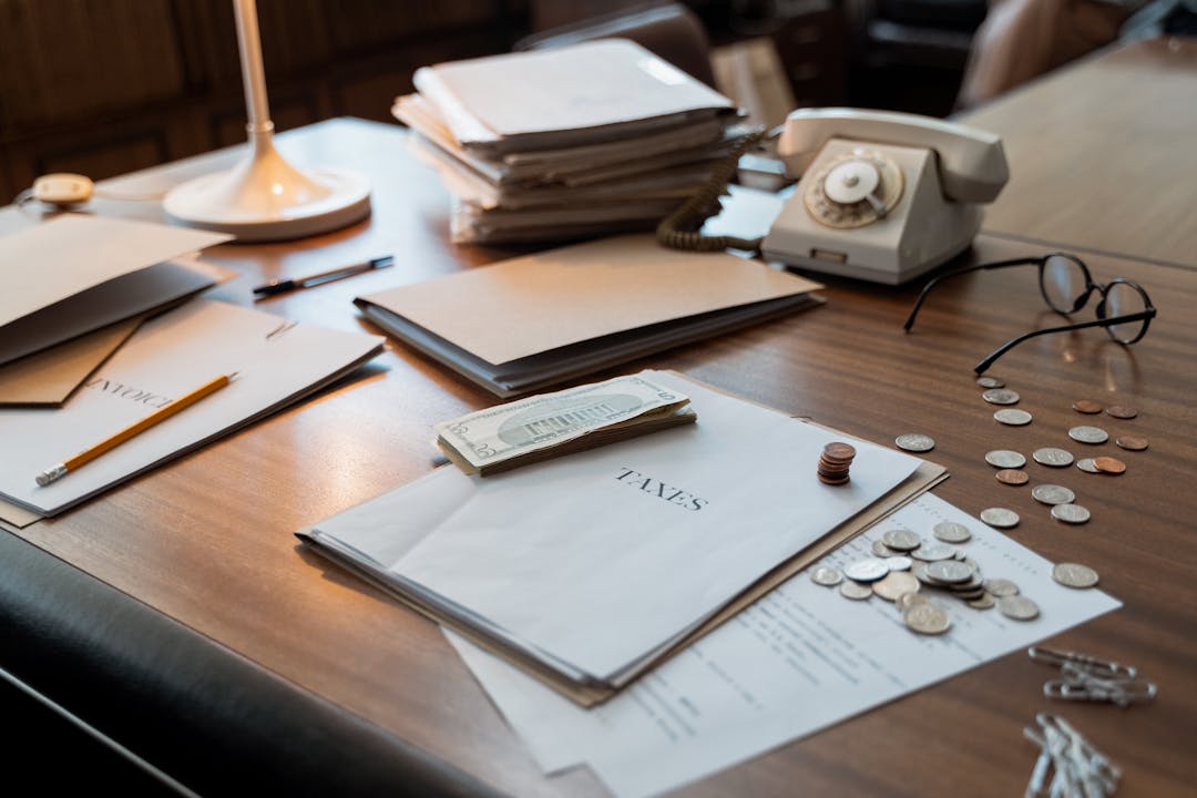 Scattered financial documents and papers covering wooden desk surface