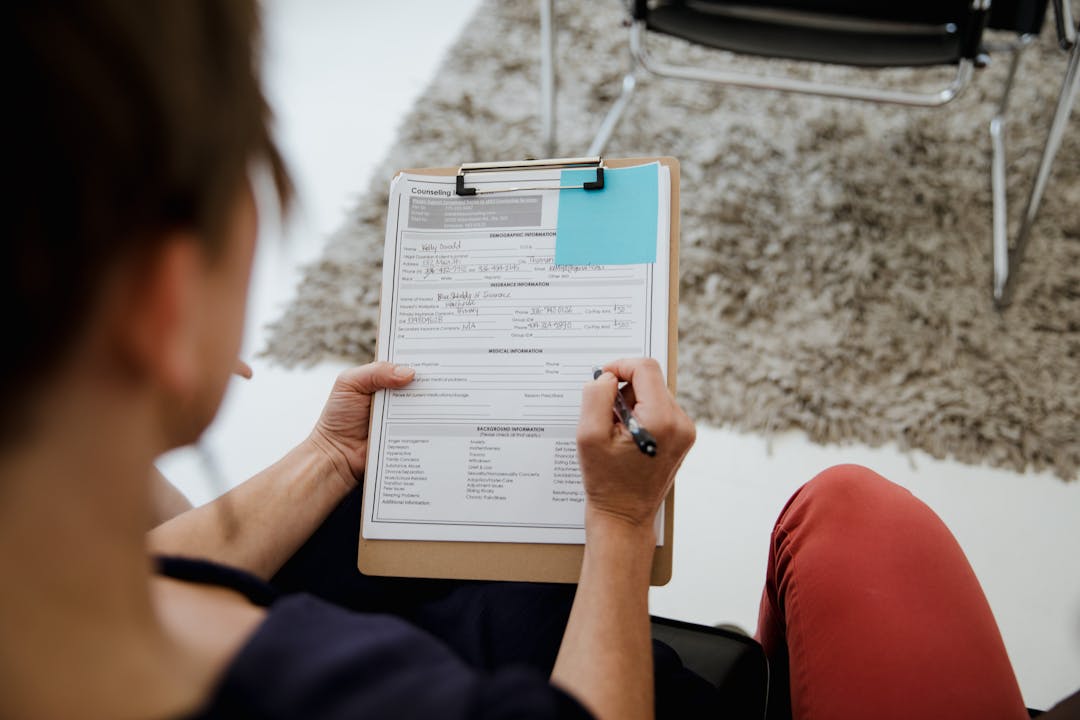 Employee at desk surrounded by undocumented process notes and scattered papers