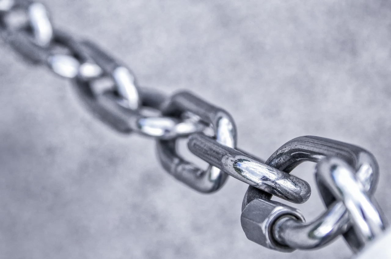 Metal chain with broken links scattered on surface showing confidentiality breach damage