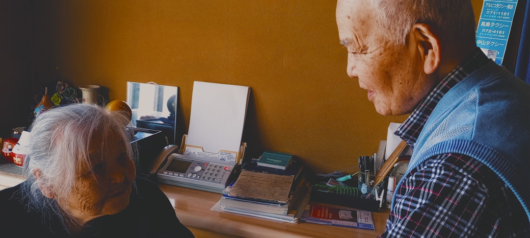 Senior person carefully reviewing legal documents at wooden desk with reading glasses