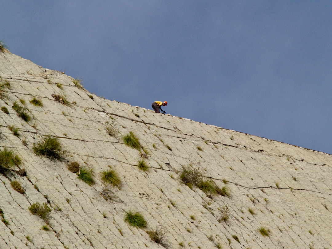 Determined climber ascending rocky mountain path toward summit representing achievement and growth