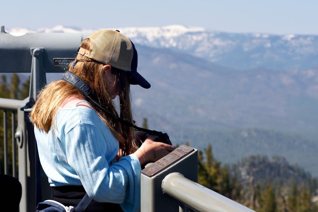 Individual with binoculars overlooking vast mountain landscape representing monitoring and oversight rights