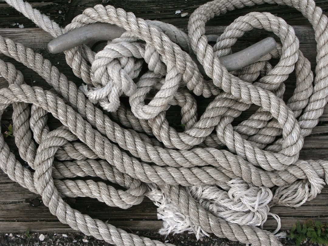 Complex tangled rope with multiple knots being carefully untangled by hands