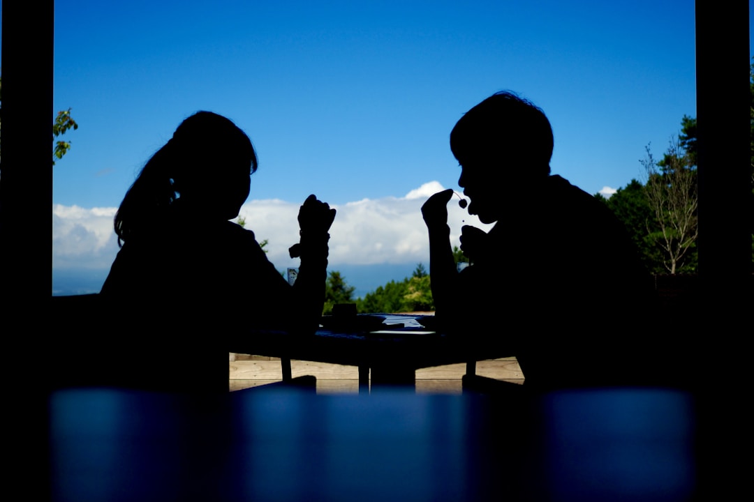 Two professionals across table during tense business negotiation discussion